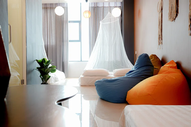 Relaxed living area with colorful bean bags, macrame wall hangings, pendant lights, and natural window lighting