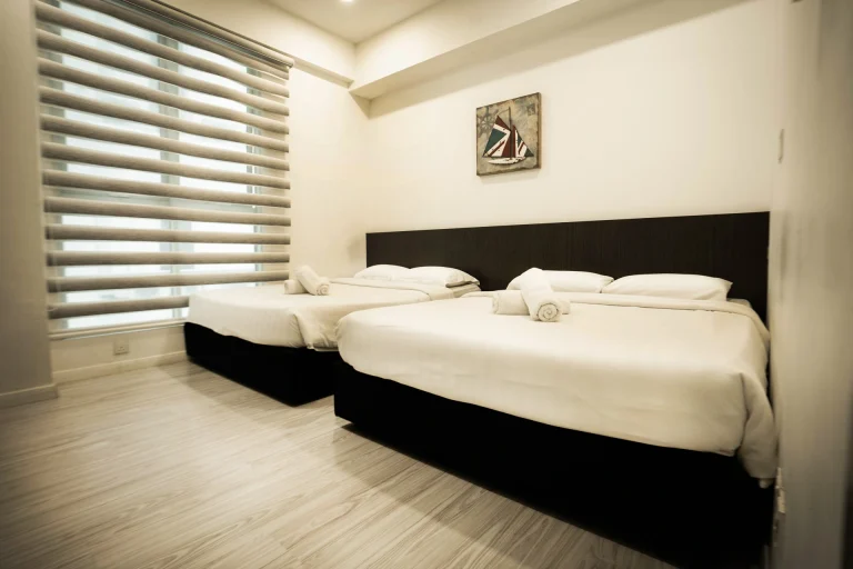 Breeze unit bedroom with two different size bed featuring black bed frames and minimalist design with window blinds