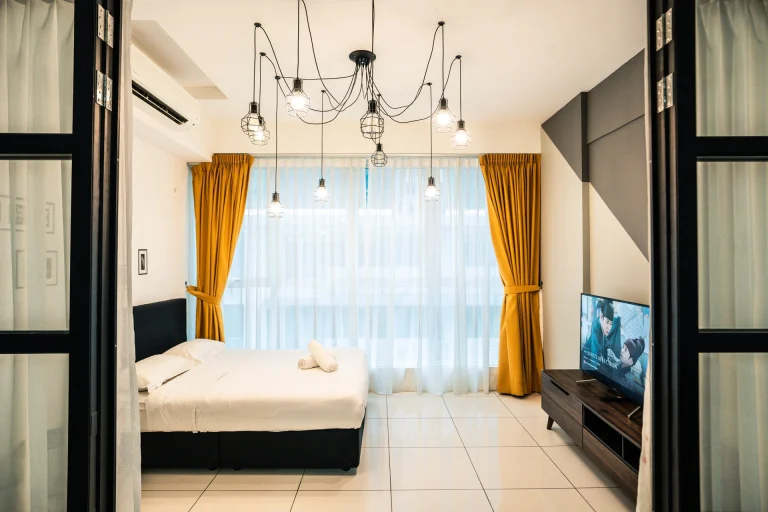 Contemporary Cocoa suites bedroom featuring with industrial pendant lighting, black bed frame, mustard curtains and flat-screen TV