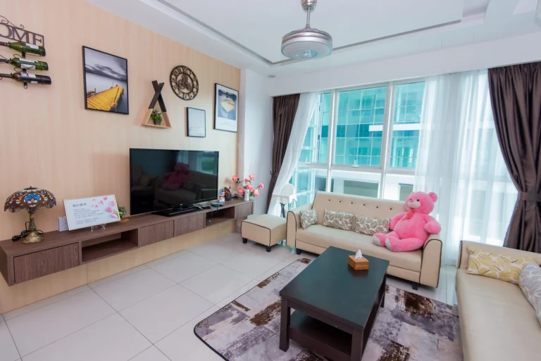 Familia Suites living room with beige sofa, pink teddy bear, wall art gallery and large windows with city views