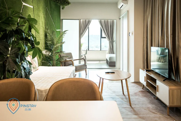 Open-plan suites with green grass wall, tropical plants, wooden furniture, and contemporary entertainment center