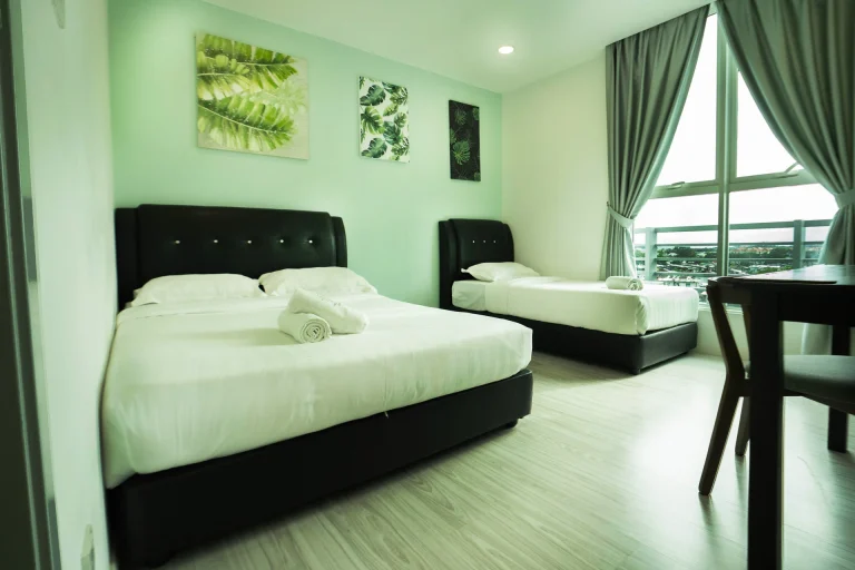 Abedroom with two different size beds with mint green walls, tropical botanical prints and black tufted headboards.