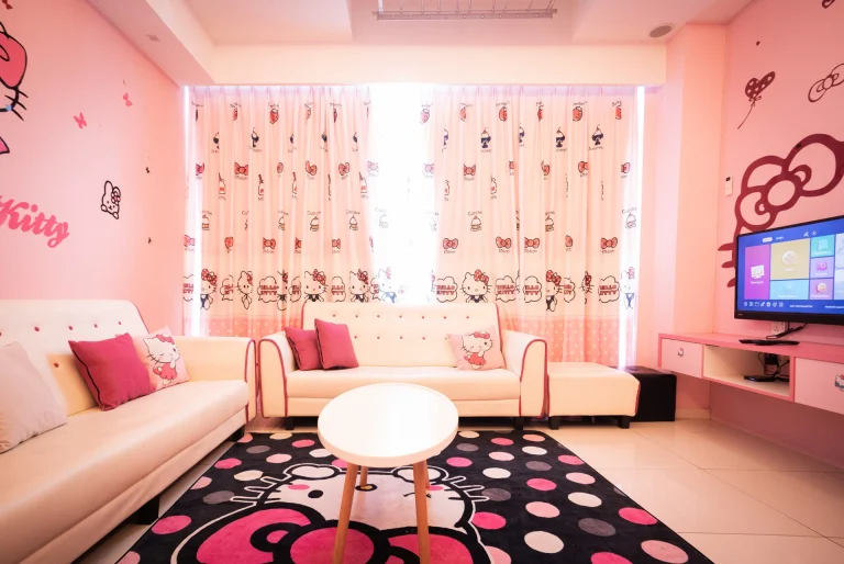 Pink living room with Hello Kitty-themed curtains, white sofa, polka dot rug and flat-screen TV