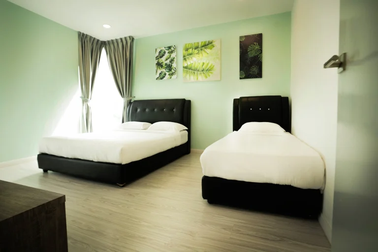 Leafy Suites accommodation with sage-colored walls, botanical prints and two different size bed with dark upholstered bed frames