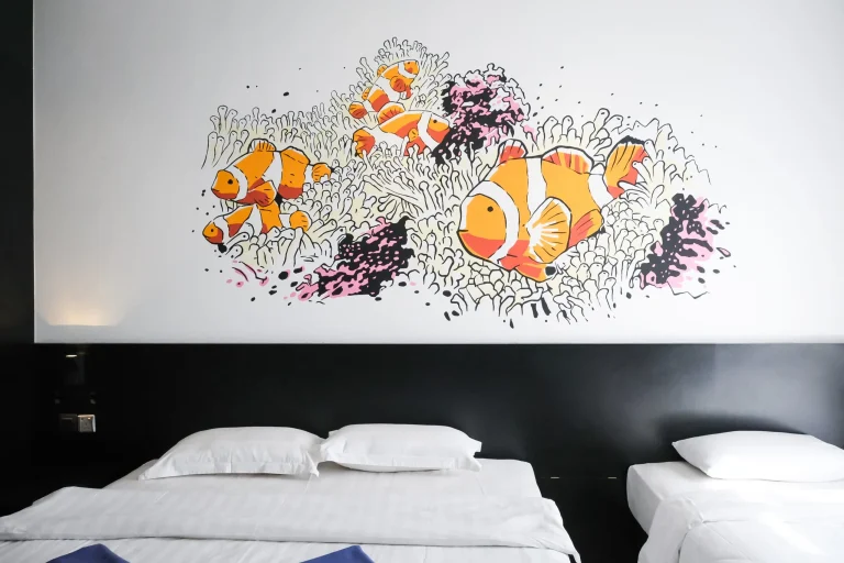 Hotel bedroom featuring Nemo Suites family room with colorful clownfish coral reef wall art and twin beds