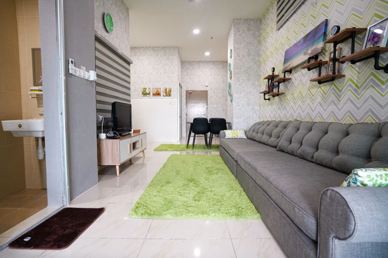 Compact living area with grey sofa and modern TV console in Serree Suites